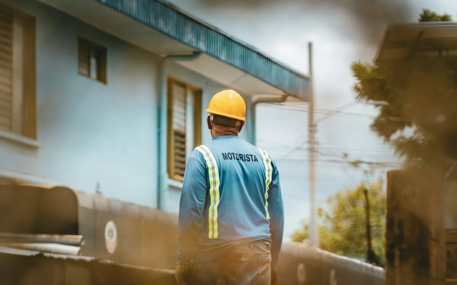 Ein Arbeiter mit Schutzhelm und Warnweste auf einem Industriegelände.