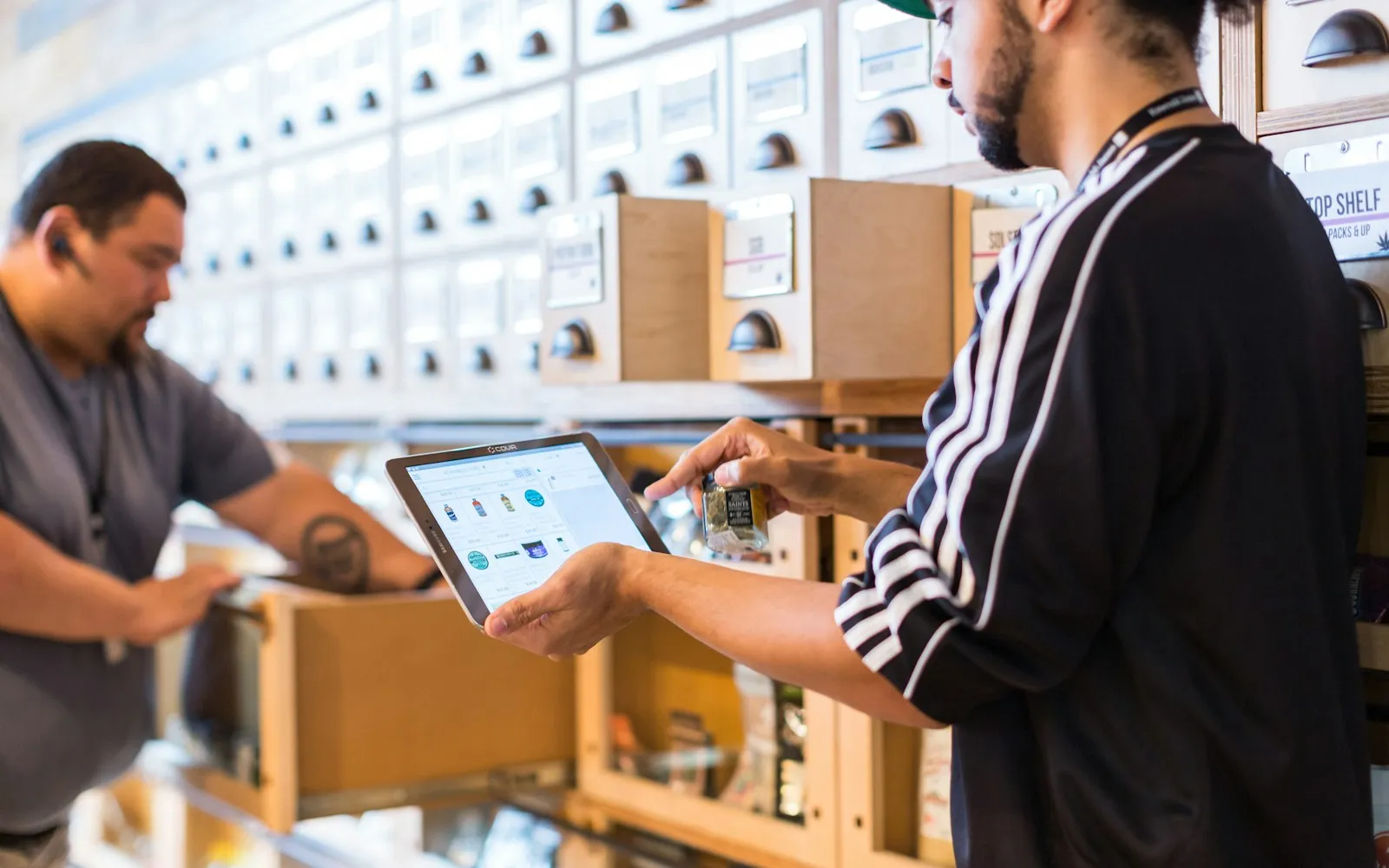 Two colleagues checking a tablet among warehouse shelves.